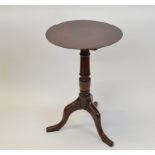 A George III oak circular snap top tripod table, having four plank top, vase support, shaped,