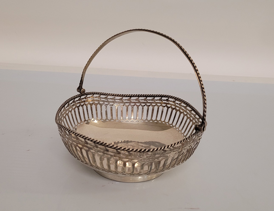 A George V silver swing handled pierced circular basket, of circular shape with shaped outline,