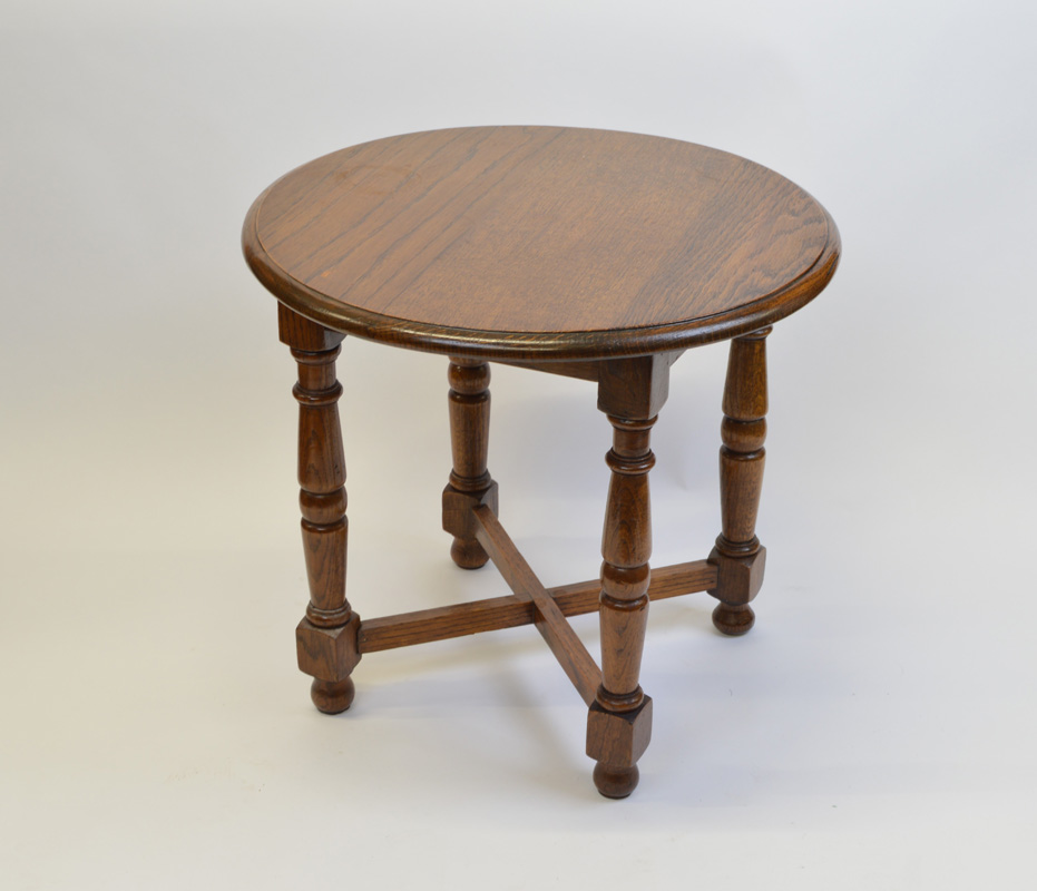 A circular oak occasional table, having four turned legs, with blocks to lower section on bun