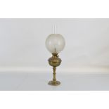 A brass oil lamp, with etched glass bowl form shade and central flue. 58cm tall