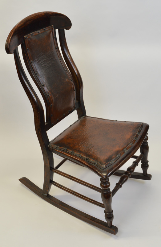 An oak framed rocking chair, having leather and stud upholstered seat and shaped back, spindle front