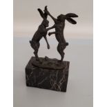 A contemporary bronze hare sculpture, of boxing hares, with foundry stamp Paris signed Nick, on