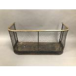 A Victorian iron and brass fire guard, 62cm wide, D shaped brass rail above mesh front