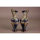 A pair of late Victorian Royal Doulton stoneware ewers, 28cm, marked 7018 and signed CA (2)