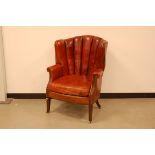An early 20th century red leather armchair, on mahogany supports with brass casters