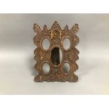 An early 20th century oriental carved wood photograph frame, 41.5cm high, with five oval holes in