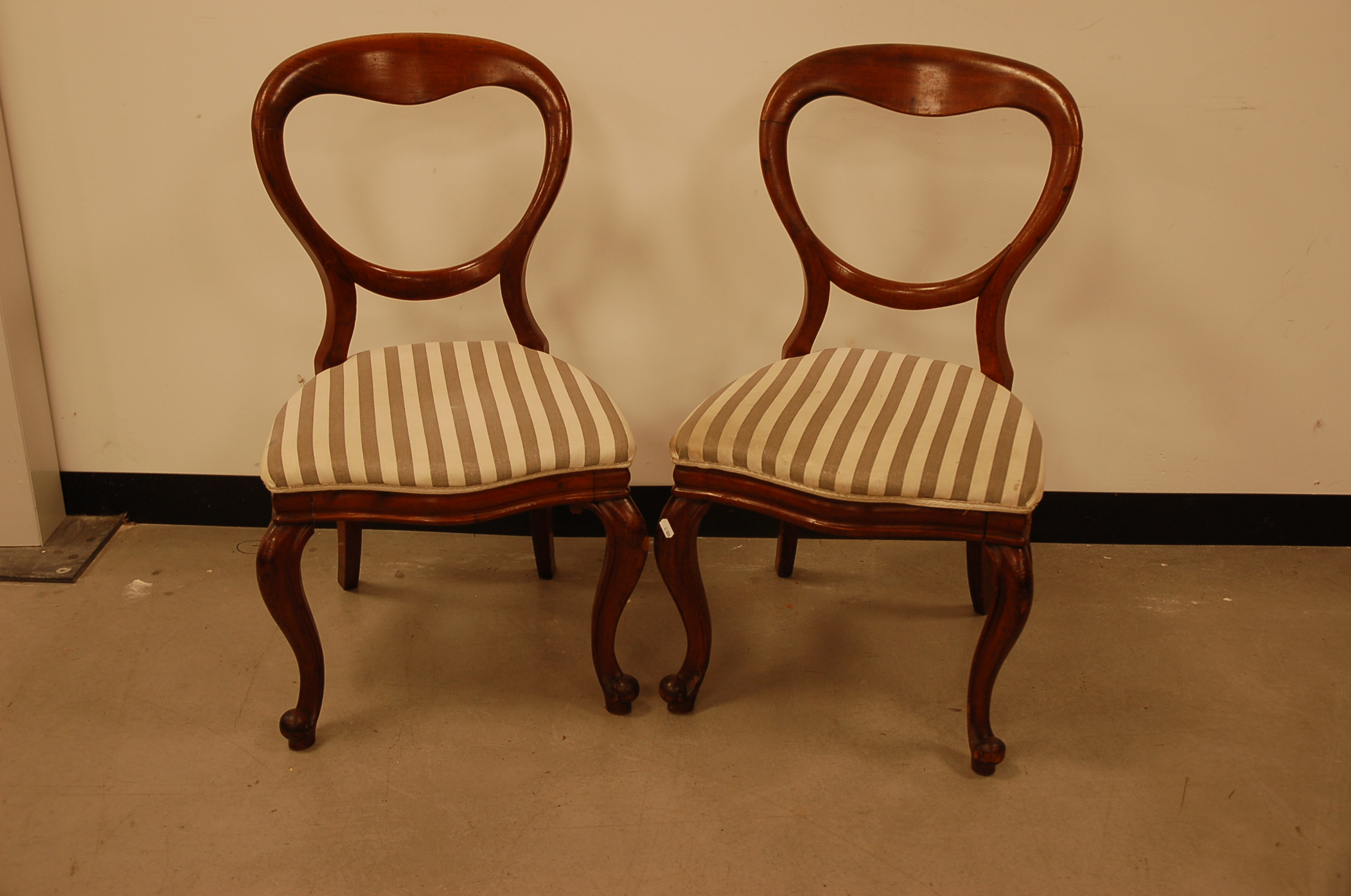 A pair of Victorian mahogany balloon back dining chairs, with later stripped upholstery