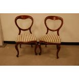 A pair of Victorian mahogany balloon back dining chairs, with later stripped upholstery