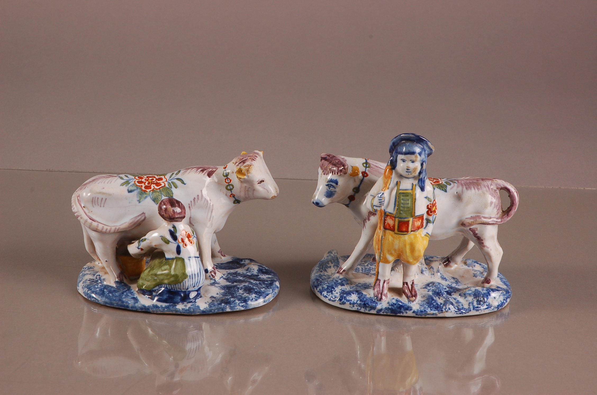 A pair of early 20th century French faience pottery figural groups, 13cm wide, one modelled a man