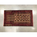 A late 19th century Middle Eastern Beluchi rug, 130cm by 75cm, the prayer matt probably from Iran or