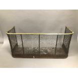 A Victorian iron and brass fire guard, 81cm wide, D shaped brass rail above mesh front