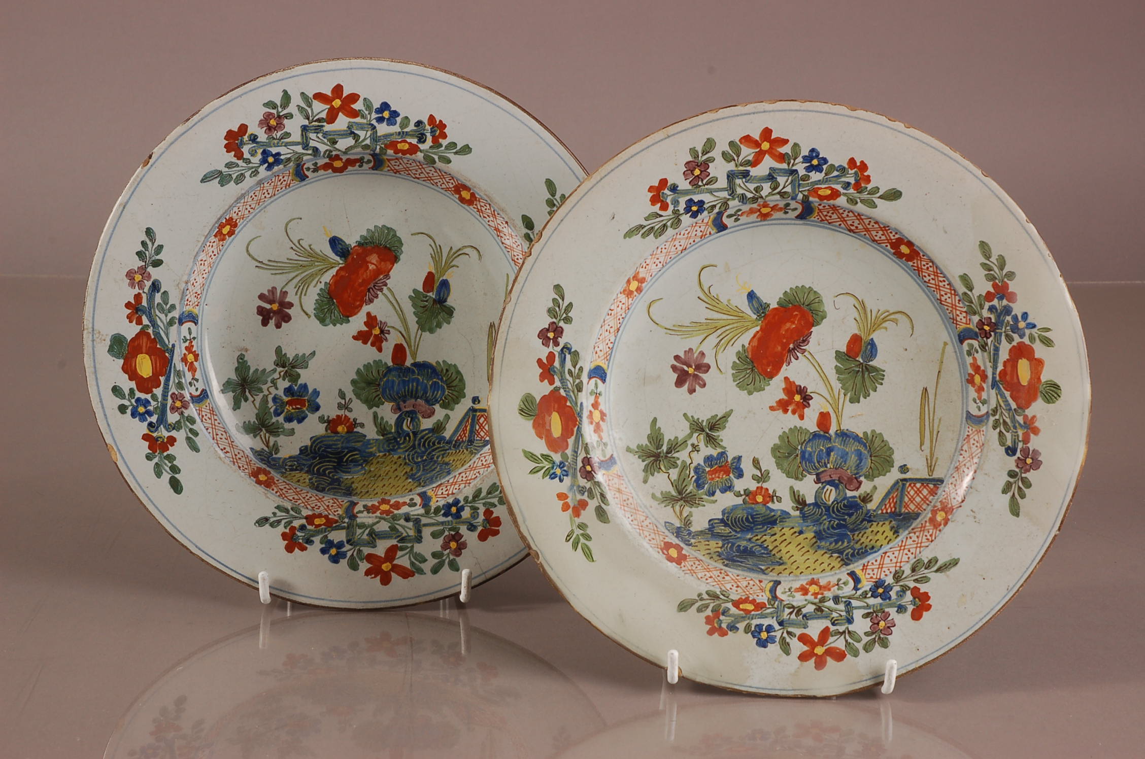 A pair of lat 18th or early 19th century French faience plates, 24cm diamter, some chips