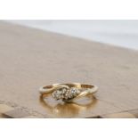 A 9ct gold three stone diamond crossover ring, ring size K, 1.7g