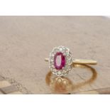 An 18ct gold ruby and diamond cluster ring, the oval mixed cut ruby surrounded by brilliant cut