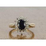 A 9ct gold sapphire and diamond cluster ring, claw set central dark sapphire surrounded by