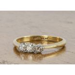 An 18ct gold and platinum three stone diamond ring, the old cuts in platinum claw settings on a fine