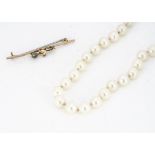 A string of uniform knotted strung cultured pearls, with a 14ct yellow gold barrel clasp, average