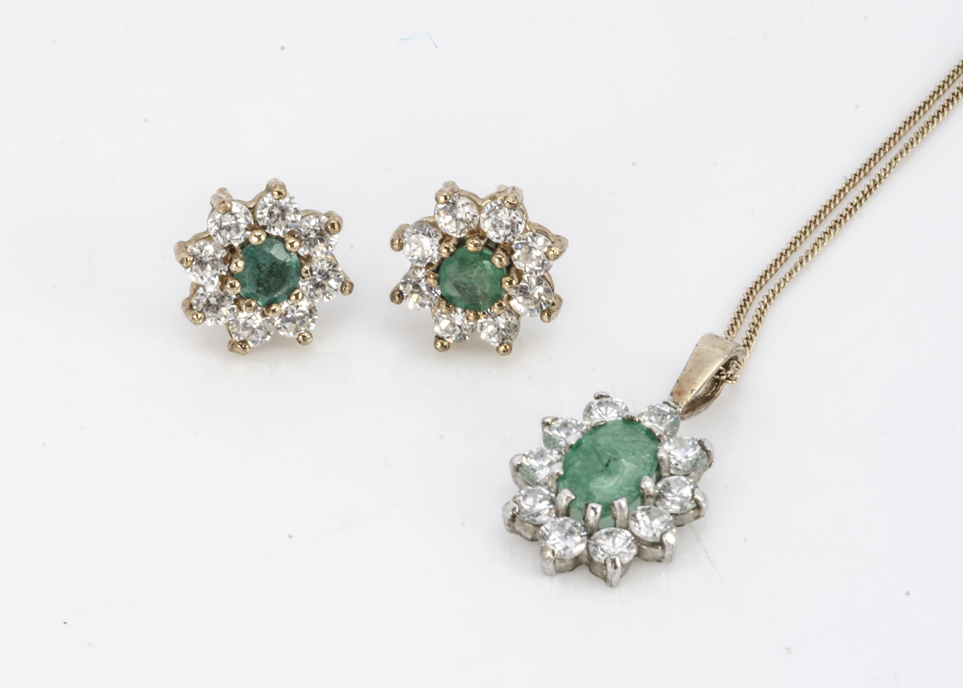 An emerald and cubic zirconia cluster pendant, together with a pair of matching ear studs,