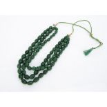 A continental triple strand carved emerald bead necklace, on a silk cord, total length 55cm, in