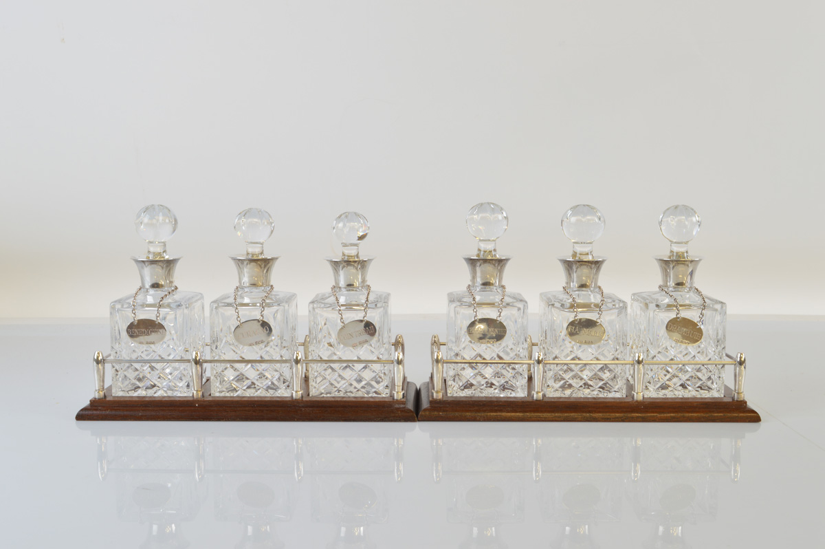 A pair of cut glass and silver mounted miniature decanter sets, the shaped bottles with hobnail