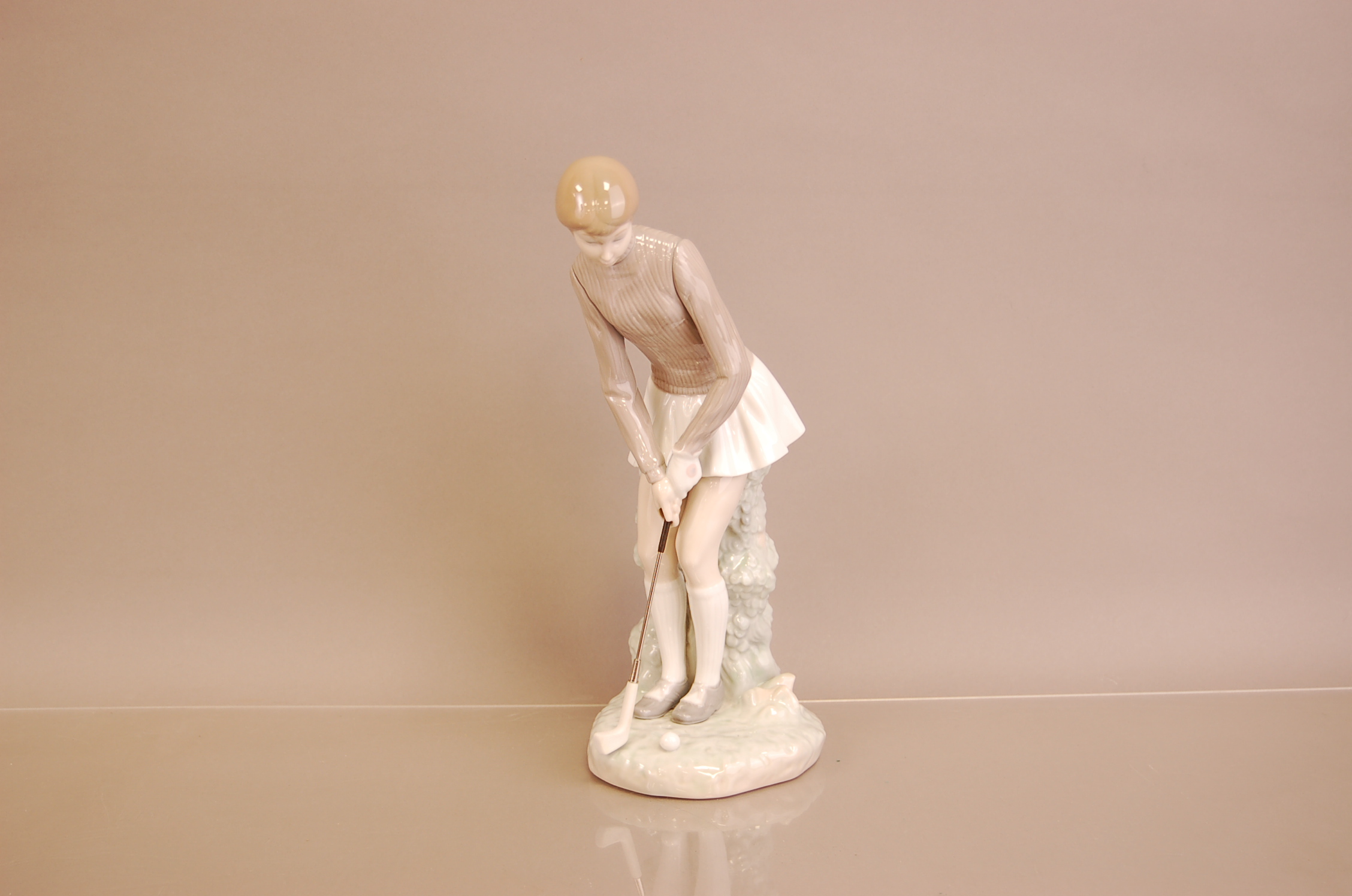 A modern Lladro figure of a golfer, 27.5cm, modelled as a lady with putter on naturalistic base,