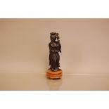 A vintage Chinese carved figure, 17cm high, on wooden base, damaged, possibly cherry amber