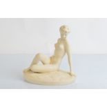A Royal Dux pottery figure modelled as a seated nude female, on a naturalistic oval domed base,