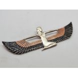 An Art Deco silver and enamel brooch, modelled as an Egyptian goddess with winged cloak, depicted