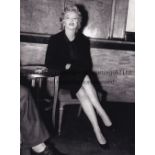 MARILYN MONROE A B/W 9" X 7" photo of the actress sitting beside a table. Copyright stamped on the