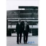 JOHN GILES Autographed 12 x 8 colour photo showing Leeds United manager Don Revie walking away