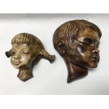 Two Art Deco style wall masks in the form of a girl and boy