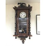 An eight day carved mahogany wall clock surmounted with a carved eagle.