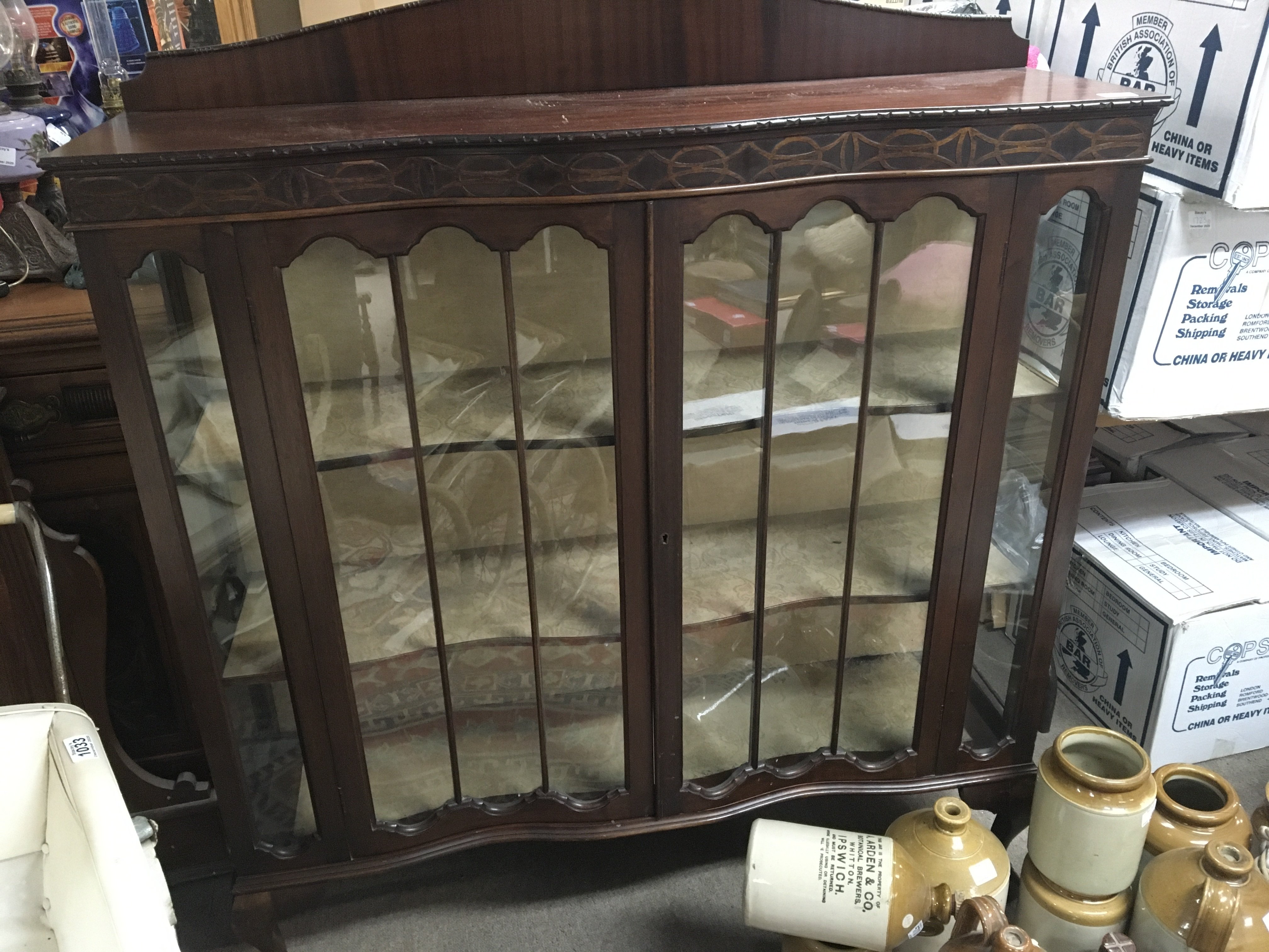 A Mahogany display cabinet with glazed doors enclosing shelfs on ball and claw feet. one end glass