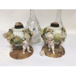 A pair of late 19th century porcelain oil lamps in the form of baskets supported by cherubs marks to