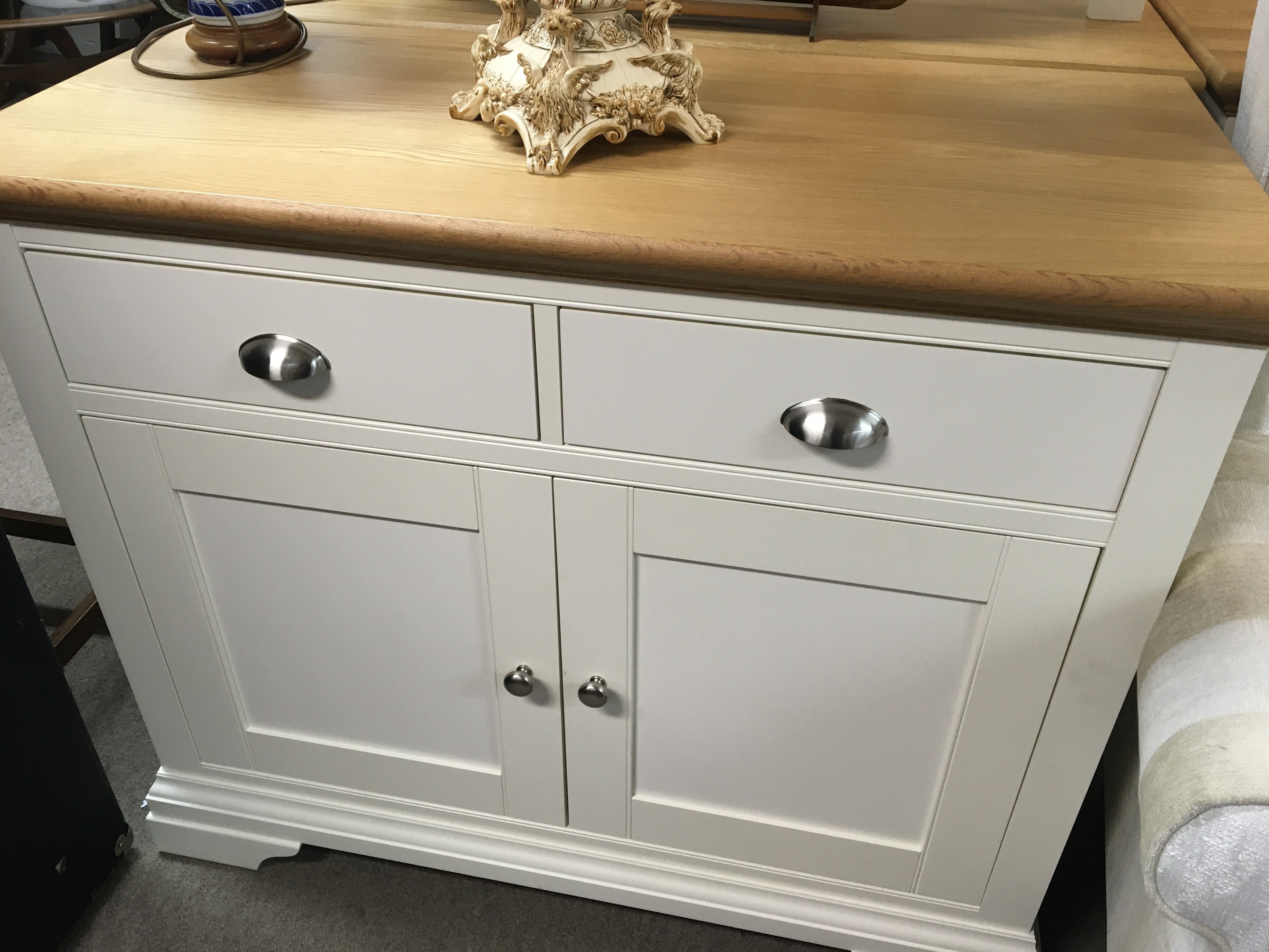 A modern white and light oak cabinet with a rectangular top above two drawers and cupboards