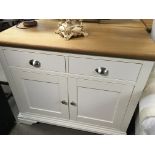 A modern white and light oak cabinet with a rectangular top above two drawers and cupboards