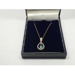 A gold pendant set with a central blue topaz and d