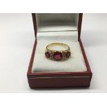 An 18ct gold ring set with three red stones and sm