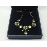 A boxed necklace set with peridots, seed pearls an