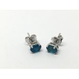 A pair of silver studs set with neon blue apatite.