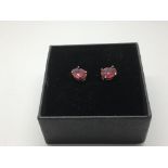 A pair of silver studs set with treated rubies.