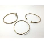 Three 9ct gold bangles, one in the form of a cat's