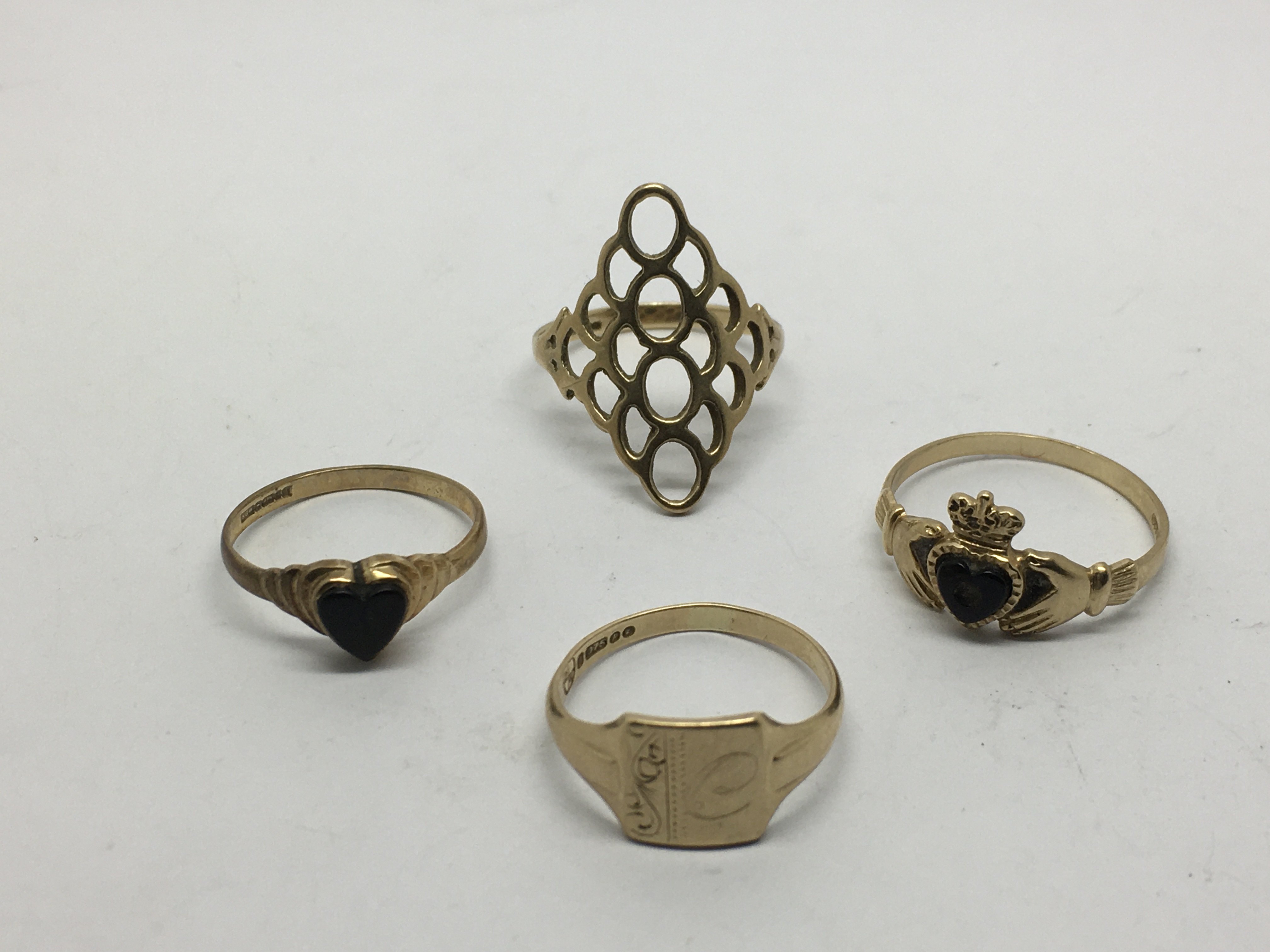 Four gold rings, two inset with onyx, approx 7g.