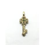 A 9ct gold key pendant set with diamonds and emera