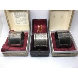 Three cased silver napkin rings.