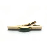 A 14k gold tie clip set with a green stone, approx
