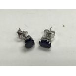 A pair of silver studs set with sapphires.