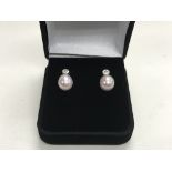 A pair of 9ct white gold diamond and pearl stud ea