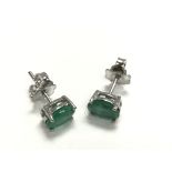 A pair of silver studs set with emeralds.