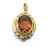 A yellow metal pendant set with a facet cut amber